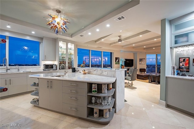 kitchen featuring sink, gray cabinets, and a kitchen island with sink