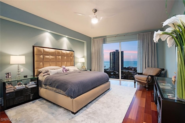 bedroom featuring a water view, ceiling fan, access to outside, and hardwood / wood-style flooring