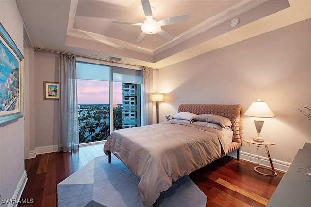 bedroom featuring dark wood-type flooring, a raised ceiling, and ceiling fan