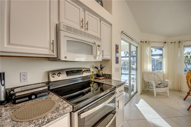 kitchen featuring light tile patterned flooring, double oven range, dark stone counters, and white cabinets