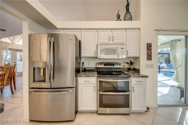 kitchen featuring white cabinetry, plenty of natural light, stainless steel appliances, and dark stone countertops