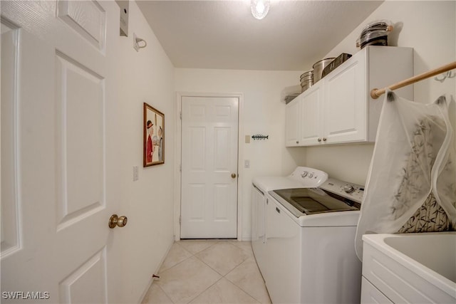 laundry area with cabinets, washer and dryer, and light tile patterned floors