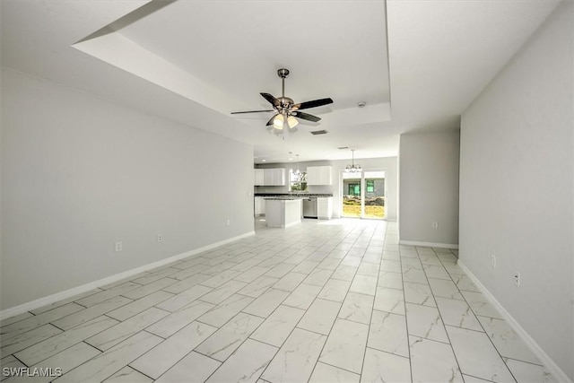 unfurnished living room with ceiling fan and a tray ceiling