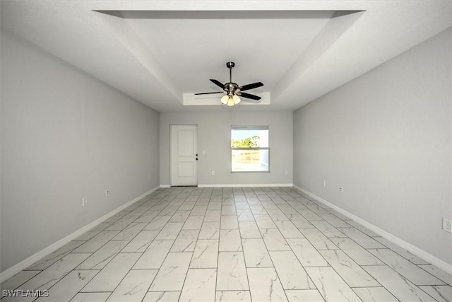 empty room with a raised ceiling and ceiling fan