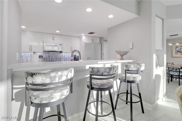 bar with tasteful backsplash, sink, white appliances, and white cabinets