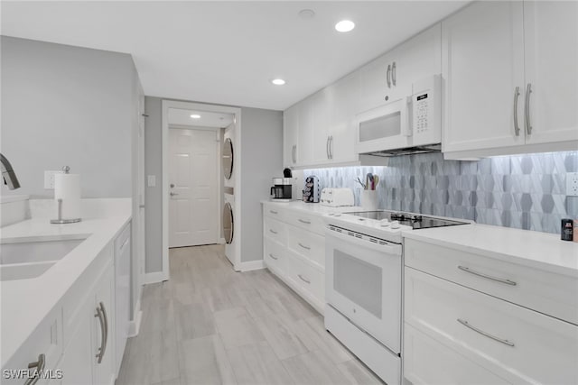 kitchen with white cabinetry, white appliances, stacked washer and clothes dryer, and tasteful backsplash