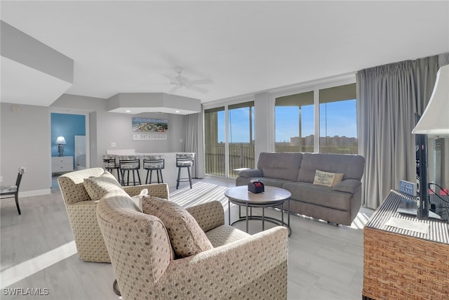 living room with ceiling fan, a wall of windows, and light hardwood / wood-style floors