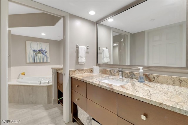 bathroom featuring vanity and tiled bath