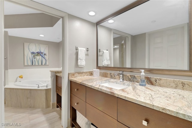 bathroom featuring a relaxing tiled tub and vanity