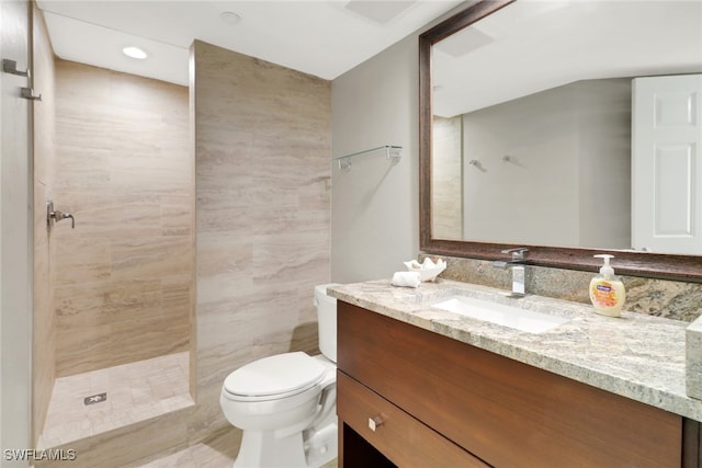 bathroom with tiled shower, vanity, and toilet