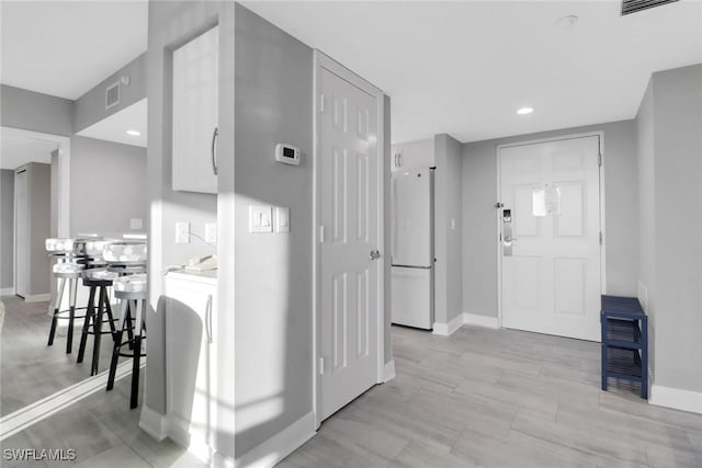 interior space featuring white cabinetry, white fridge, and a kitchen bar