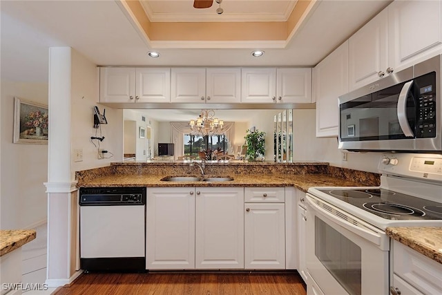 kitchen featuring a tray ceiling, sink, white appliances, and white cabinets