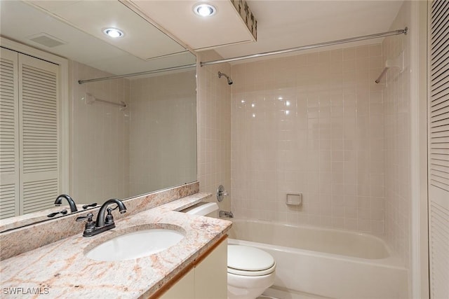 full bathroom with tiled shower / bath, vanity, and toilet