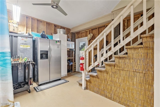 kitchen with wood walls, ceiling fan, and stainless steel fridge with ice dispenser