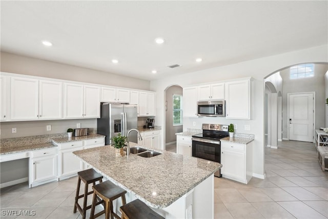 kitchen featuring an island with sink, appliances with stainless steel finishes, sink, and white cabinets