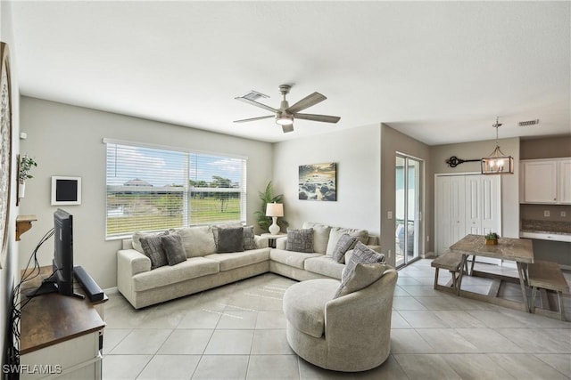 living room featuring light tile patterned floors and ceiling fan with notable chandelier