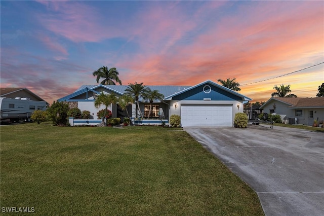 ranch-style home with a garage, cooling unit, and a lawn