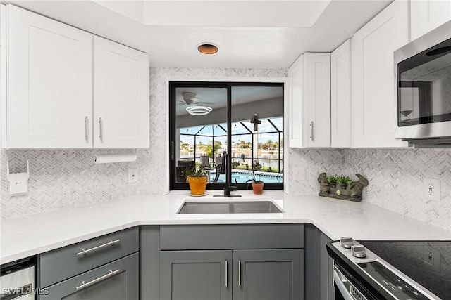 kitchen with gray cabinets, appliances with stainless steel finishes, sink, and white cabinets