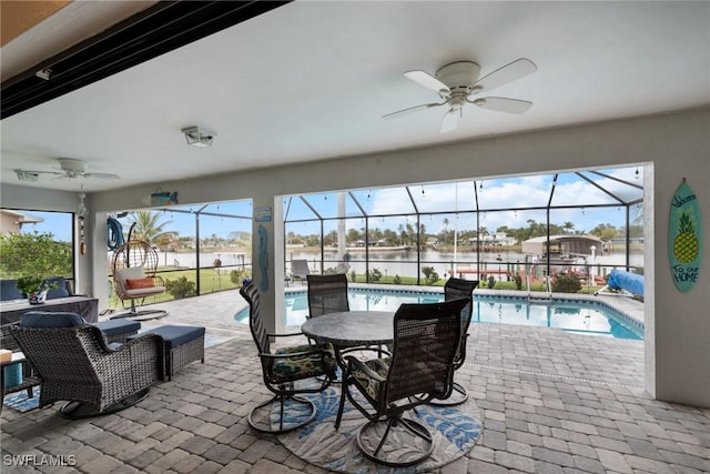 view of patio featuring a lanai, an outdoor hangout area, ceiling fan, and a water view