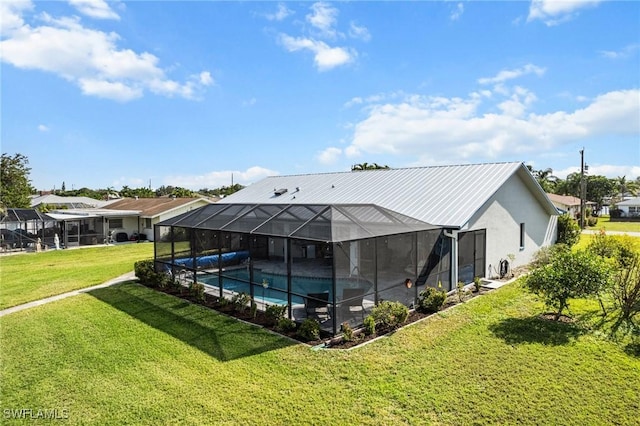 rear view of house featuring a lanai, a covered pool, and a lawn