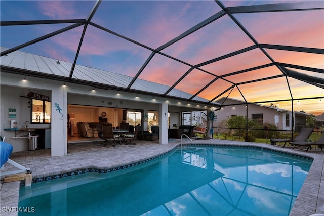 pool at dusk featuring a patio, a lanai, and an outdoor hangout area