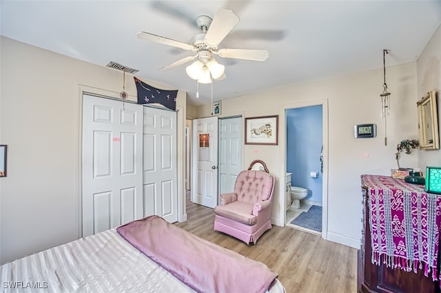 bedroom featuring multiple closets, light hardwood / wood-style floors, ceiling fan, and ensuite bathroom