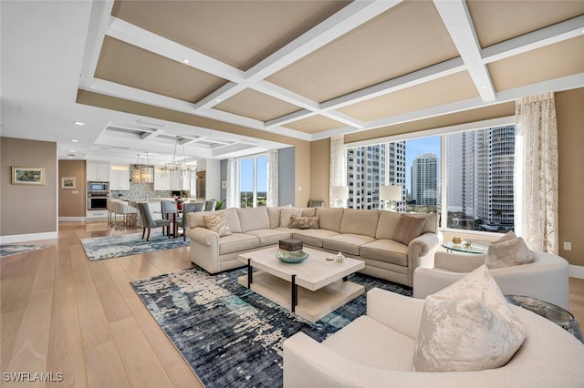 living room with beamed ceiling, coffered ceiling, an inviting chandelier, and light wood-type flooring