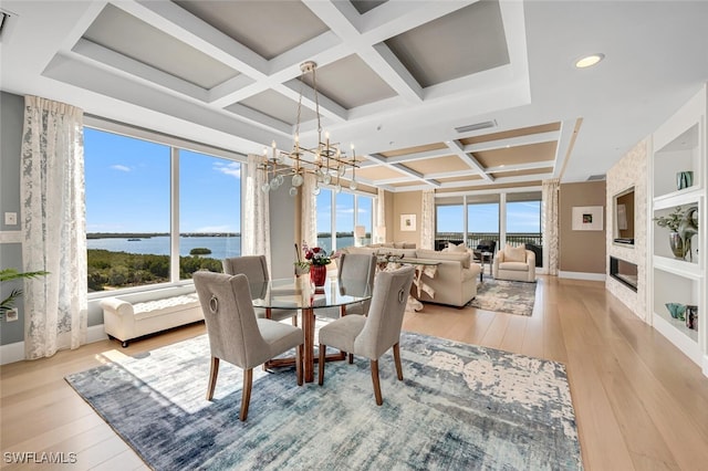 dining area with a water view, coffered ceiling, a wealth of natural light, and light wood-type flooring