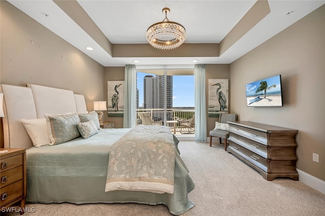 carpeted bedroom with an inviting chandelier, a raised ceiling, and access to outside