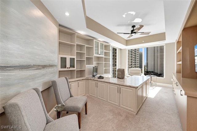 office area featuring a tray ceiling, built in features, light colored carpet, and ceiling fan