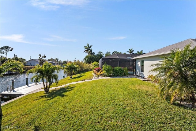 view of yard with a lanai, a boat dock, and a water view