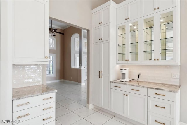 bar with arched walkways, light tile patterned floors, backsplash, a ceiling fan, and ornamental molding