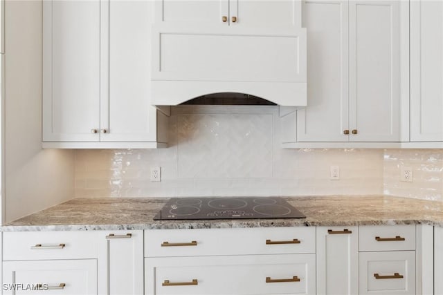 kitchen with light stone countertops, white cabinetry, custom exhaust hood, and black electric cooktop