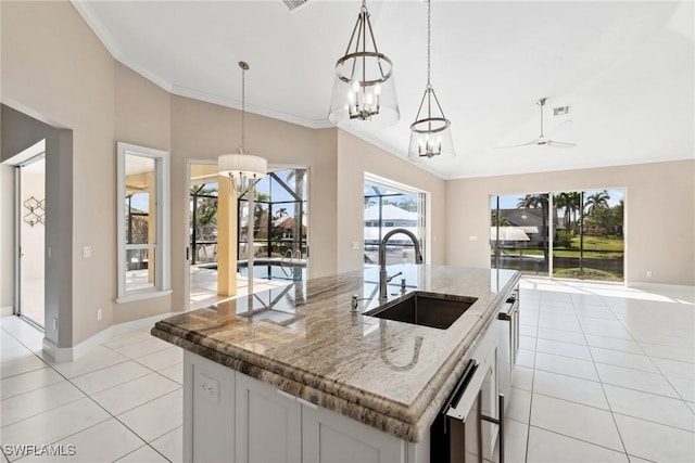 kitchen with white cabinets, decorative light fixtures, a sink, and an island with sink