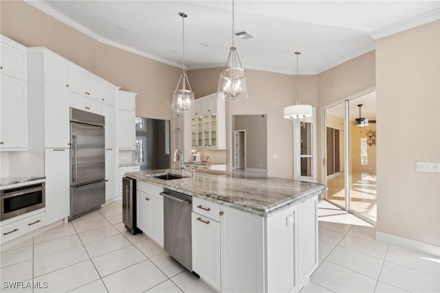 kitchen with pendant lighting, stainless steel appliances, white cabinets, a sink, and an island with sink