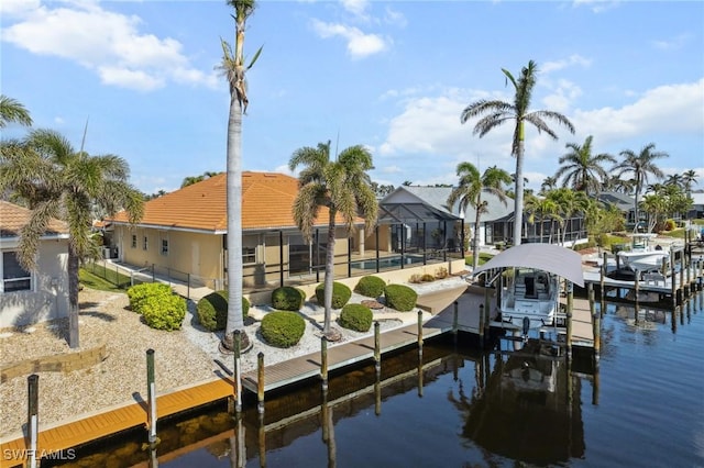 view of dock featuring glass enclosure, a water view, boat lift, and a residential view