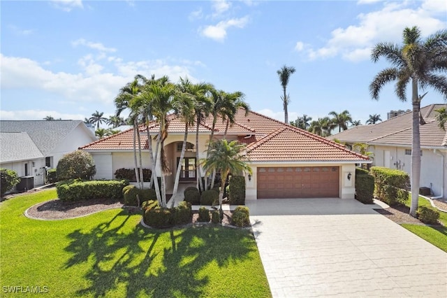 mediterranean / spanish house featuring a garage, a tiled roof, decorative driveway, a front yard, and stucco siding