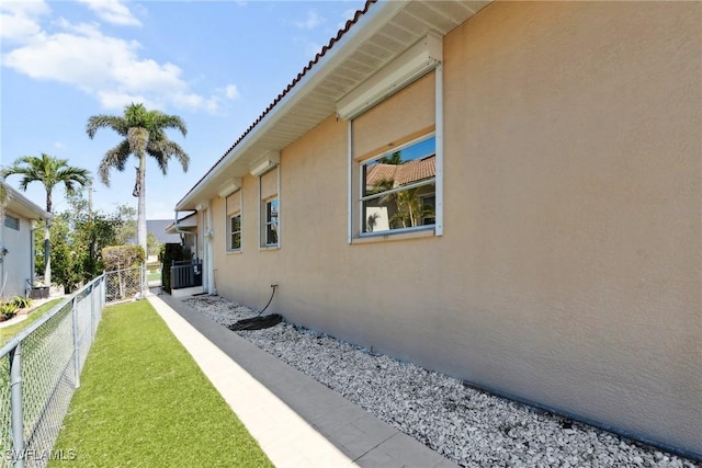 view of property exterior featuring a tile roof, fence, and stucco siding