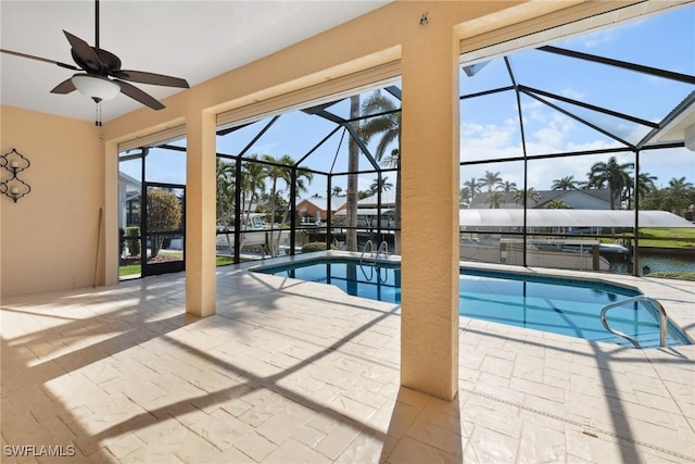 outdoor pool featuring a water view, glass enclosure, ceiling fan, and a patio area