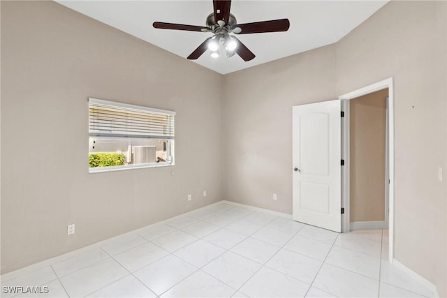 spare room with ceiling fan, light tile patterned flooring, and baseboards