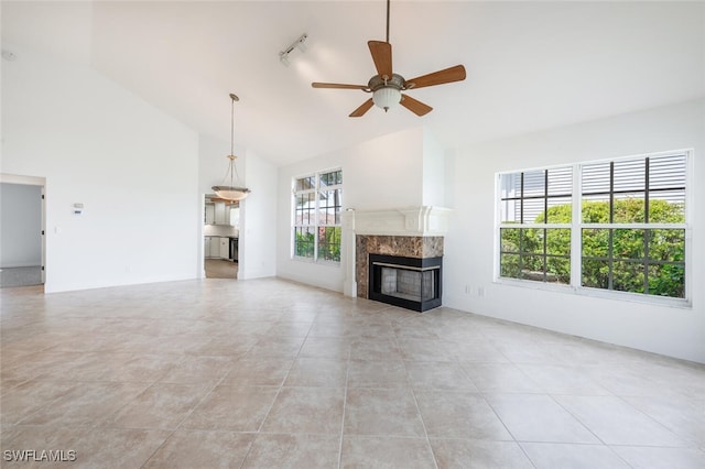 unfurnished living room featuring light tile patterned floors, rail lighting, a premium fireplace, a ceiling fan, and high vaulted ceiling