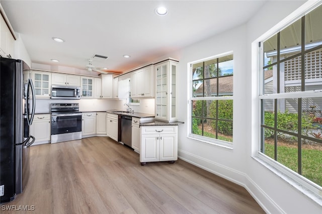 kitchen featuring stainless steel appliances, a wealth of natural light, a sink, and baseboards