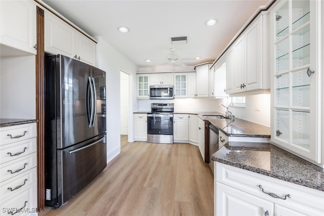 kitchen featuring a sink, white cabinetry, appliances with stainless steel finishes, light wood-type flooring, and glass insert cabinets