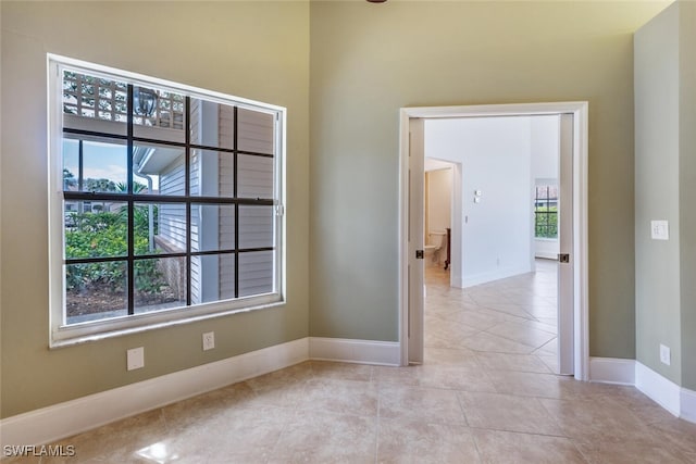 empty room featuring light tile patterned flooring and baseboards