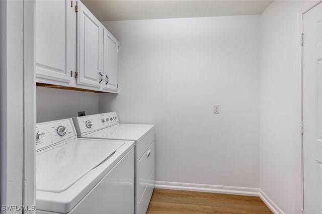 laundry area with light wood-type flooring, baseboards, cabinet space, and washing machine and clothes dryer