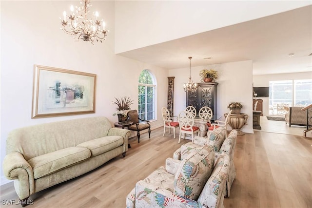 living room with plenty of natural light, a notable chandelier, and light hardwood / wood-style flooring