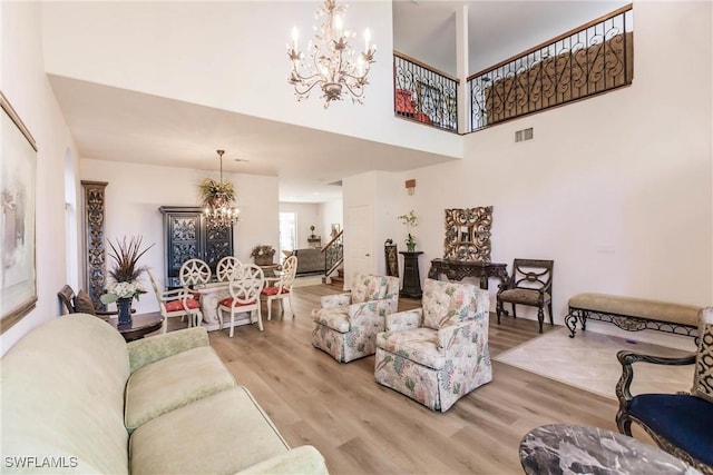 living room featuring hardwood / wood-style floors, a towering ceiling, and a chandelier