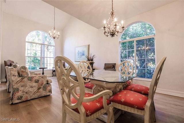 dining space featuring hardwood / wood-style flooring, vaulted ceiling, and a notable chandelier