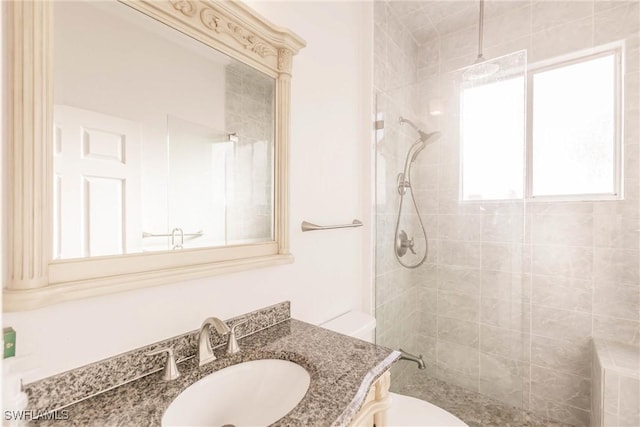 bathroom with vanity, toilet, and a tile shower