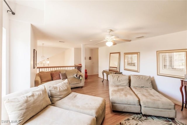 living room with ceiling fan with notable chandelier and light hardwood / wood-style floors